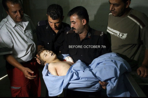 A group of four men gather around the body of a child. The little boy is dead and in the arms of two of the men. He is wrapped in a blue sheet. Text on image reads: BEFORE OCTOBER 7TH