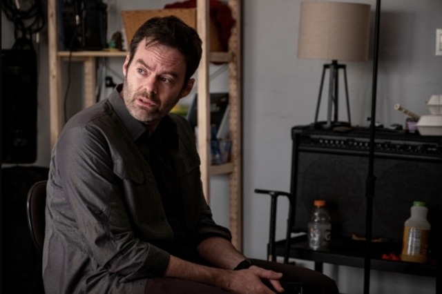 Bill Hader as Barry Berkman sitting and looking off to the side. In the background is a Gatorade and juice bottle, speaker, lamp, and shelf