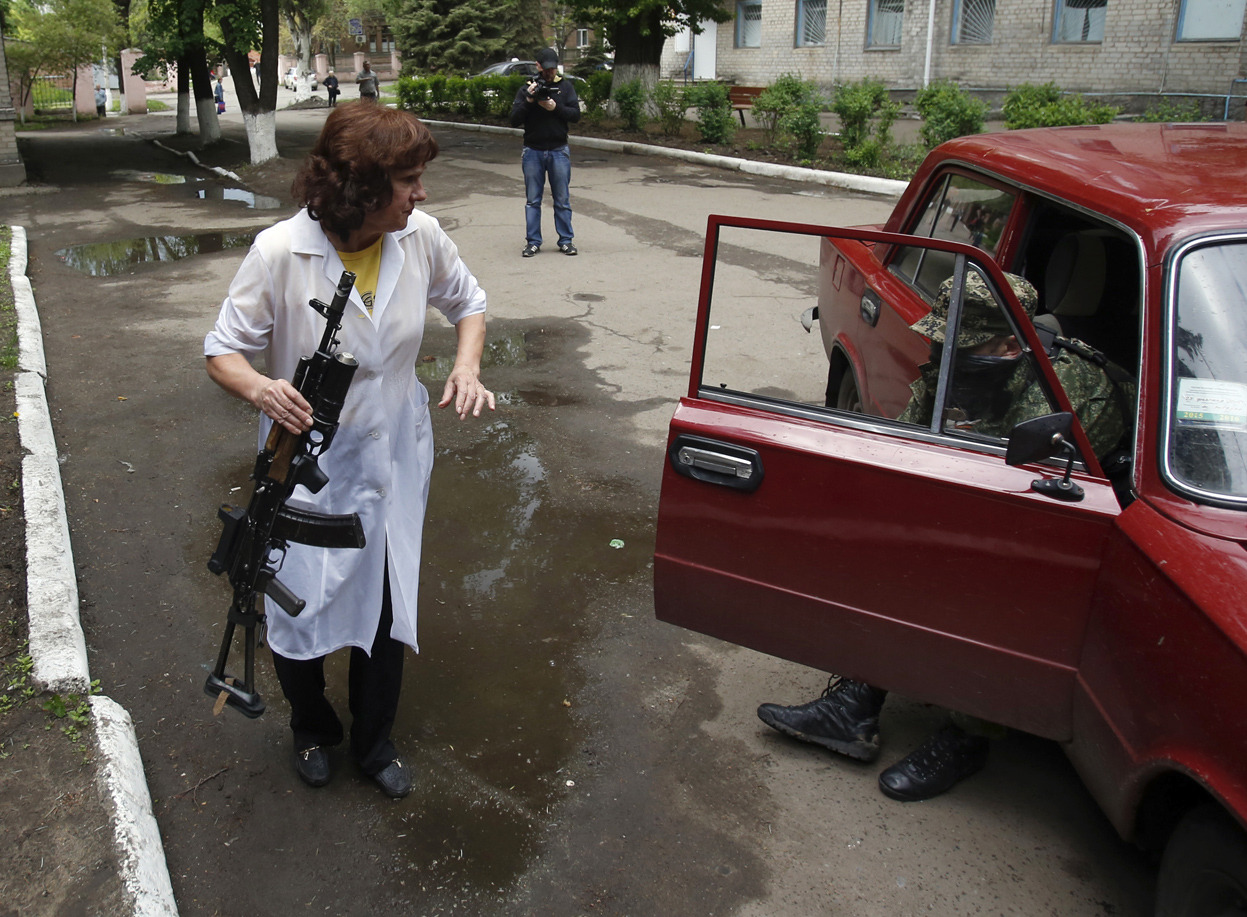 From What the Hell Is Going on in Ukraine?, one of 40 photos. A nurse holds a weapon as she helps a wounded pro-Russian gunman to exit a car in front of a hospital in Slovyansk, eastern Ukraine, on May 5, 2014. Ukrainian troops fought pitched gun...