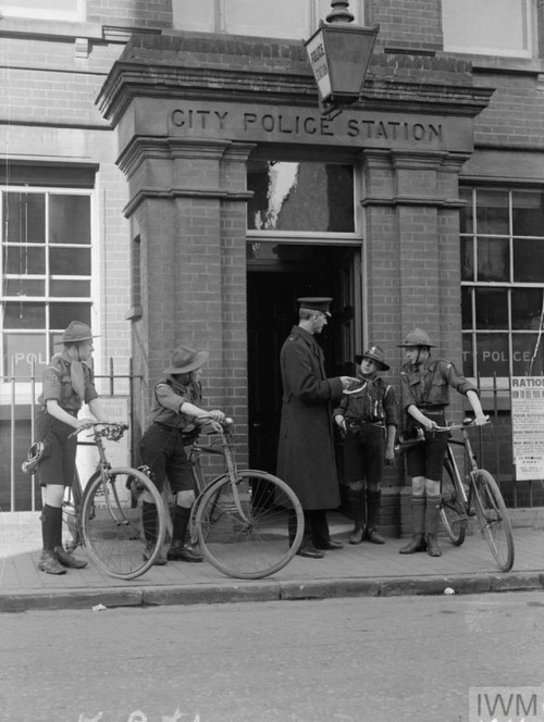 Boy Scouts receive instructions from an officer at the local policestation for sounding the “All Cle