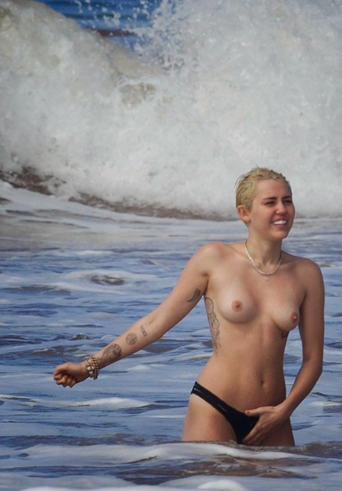 prettylittlerulebreaker:  thenudecity:  Here is Miley Cyrus topless wearing only her bikini bottoms and enjoying the surf at the beach in Hawaii. Cyrus  seems to be going out of her way to show us her naked body in 2015. And  this time around her boobs