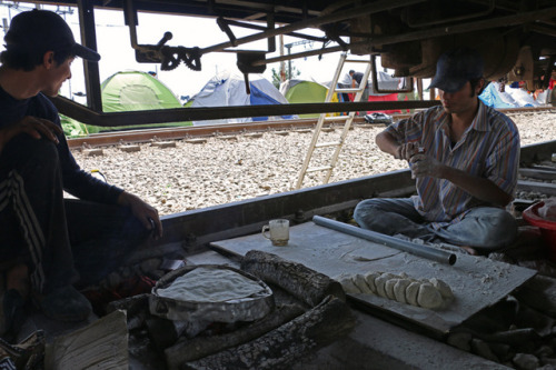 Under an old cargo train refugees living in the camp are baking bread. An NGO has ordered it for the