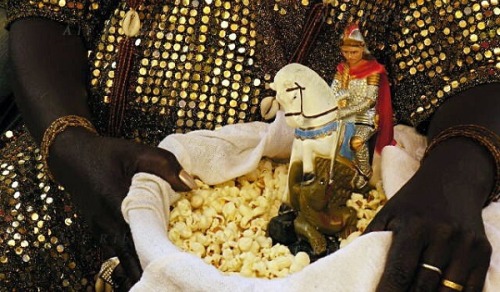 Mother of Candomble saint holds a basket with popcorn and a statue of Saint George. In Brazil, St. G