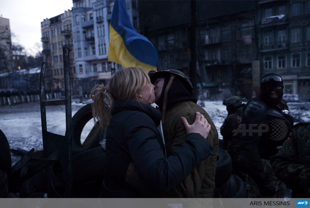 UKRAINE, Kiev : A young woman kisses an anti-government protester at at a road bloc barricade in Kiev on February 1, 2014. President Viktor Yanukovych on January 30 accused the opposition of inflaming tensions in Ukraine’s crisis but also admitted...