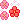 pixel art of three flowers; two pink and one red, they all swirl around in a circular motion, and around them are some sparkles