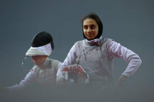 modernfencing:  [ID: a foil fencer unhooking after a bout, looking a little rueful.] Negin Kafi (right), after fencing Nam Hyun Hee at the 2015 Asian Fencing Championships! 