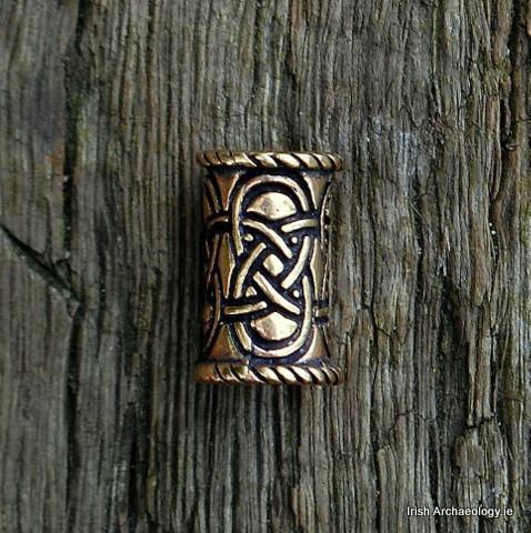 This bronze hair bead is decorated with an interlace design inspired by Celtic art. It is worn by pa