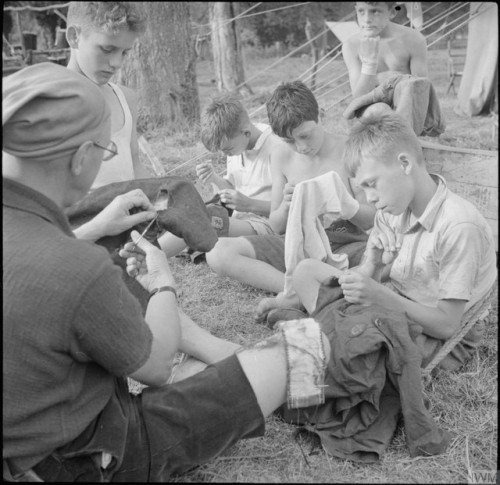 Boy Scouts patching & mending their clothes at a fruit-picking camp near Cambridge (1943), assis