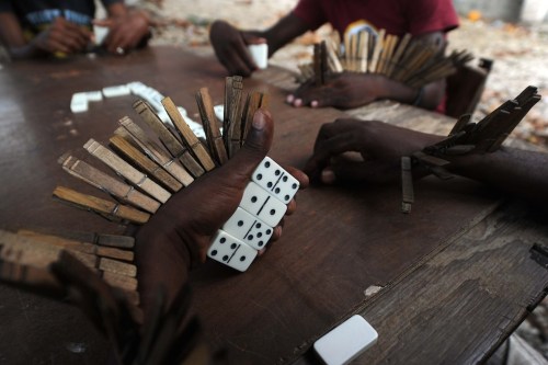 Men with clothespins attached to their hands and arms play dominoes on September 22, 2014 in the Dez