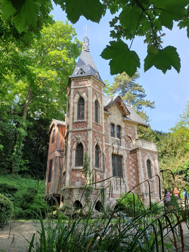 a photo of a small castle in redbrick with yellow stone carving, with a tower and ornate decorations 