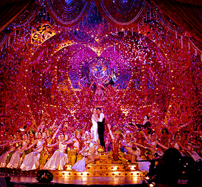 A luxurious red curtain closes over a glittering stage packed with dancers.