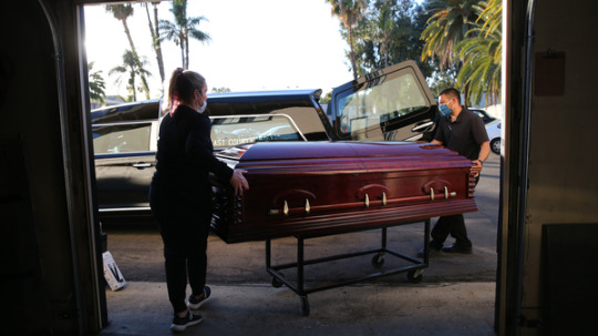 Embalmer and funeral director Kristy Oliver (left) and funeral attendant Sam Deras load the casket of a person who died after contracting COVID-19 into a hearse in El Cajon, Calif. People who work in hospitals and in funeral homes are witnesses to the loss than many Americans can avoid.