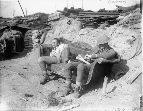 Two artillery officers, one reading and one asleep on a sofa outside a dugout in the sunshine near Z