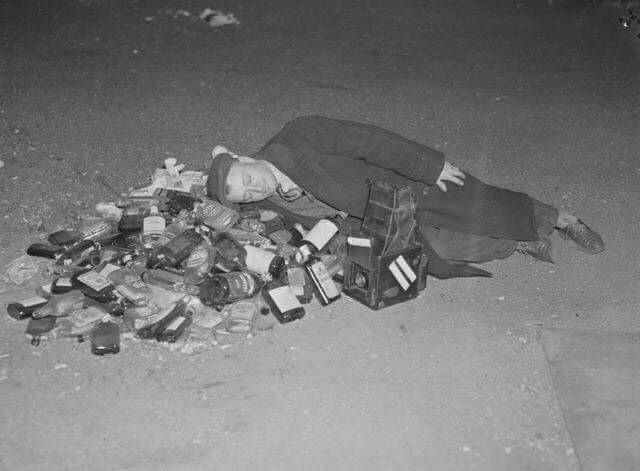 Man rests on empty bottles of booze during the end of Prohibition, 1933.