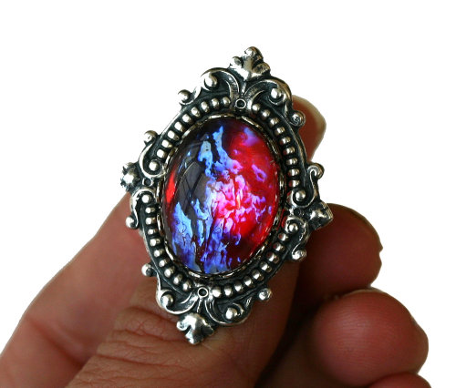 wickedclothes:  Dragon’s Breath Fire Opal Nebula Ring Resting in an ornate, sterling silver setting, this Victorian style ring features a pink fire opal. Resembling the image of a nebula, the pink fire opal shows blue tints when in the light. Sold on