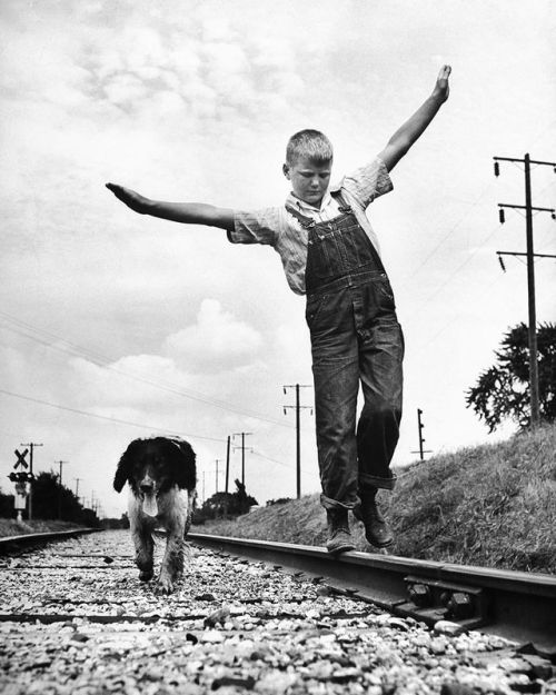 Larry Jim Holm, 12, with Dunk, his spaniel-collie mix, walking rail of railroad tracks in Oskaloosa,