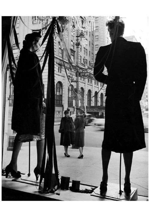 Two elegantly dressed women standing on corner of Fifth Avenue and 58th Street across from mannequin