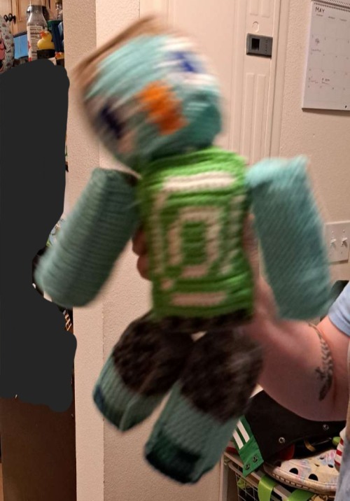 Image 6: a photo of the juppet doll being shaken violently by a person mostly offscreen.