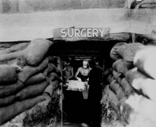 A surgeon operating on an injured American soldier, wounded from a Japanese sniper, in an undergroun