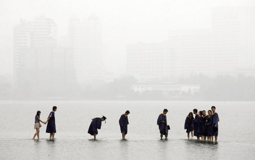 unearthedviews: Wuhan, China: Students in graduation robes stand on a stone bridge submerged by floo