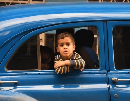 A young boy pokes his head out of a vintage car on the streets of Havana. Read more about Havana car