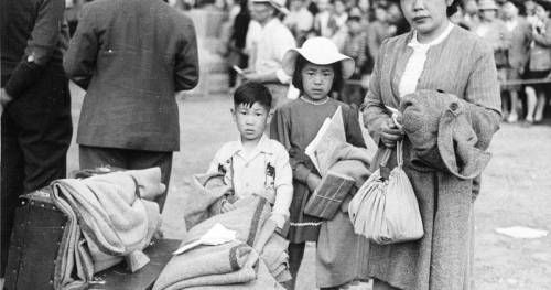 Japanese-Canadian family waiting to board trains to take them to internment camps in Canada, WWII