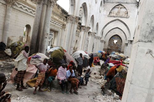 Somali refugees sit among makeshift shelters on August 12, 2011 in the ruins of the Mogadishu Cathed
