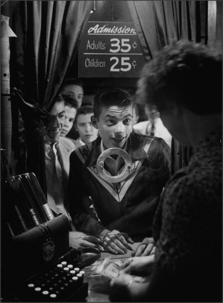 Teens, 1954Teenage boy peering through ticket booth window at local movie theater.