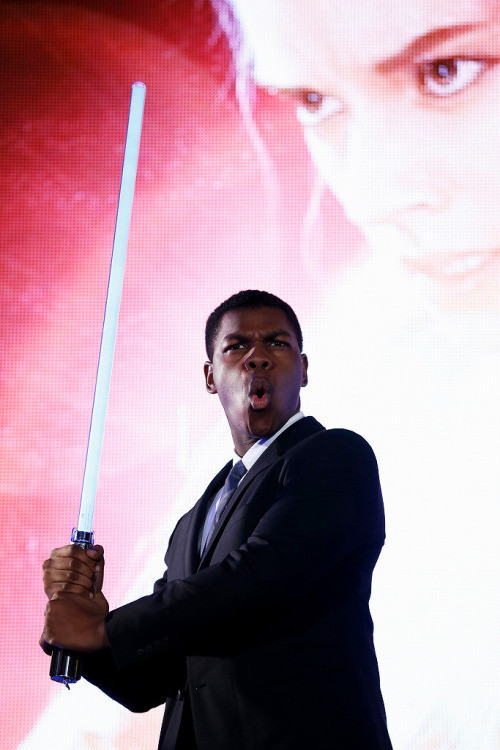 soph-okonedo: John Boyega poses with a lightsaber at the ‘Star Wars: The Force Awakens’ fan event 