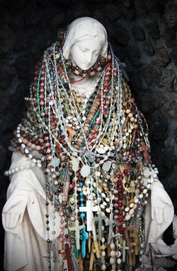 deus-meus-et-omnia:‘Madonna’ - photographed by Stephanie Mancini.  This statue sits outside a gas station in Italy.  She is covered in rosaries by passersby.