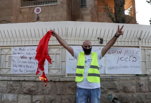 A Palestinian Christian sports a victory sign as he holds a burning Turkish flag outside the Turkish