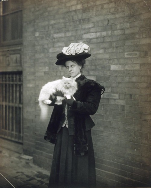 Unidentified woman standing outside with her cat, ca. 1905