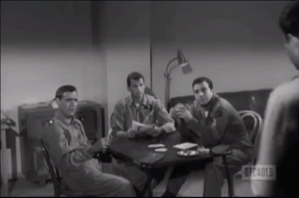 1950s air force guy steps into a room with three other guys and at least one light bulb for a change