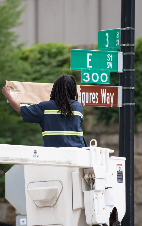 Unveiling Hidden Figures Way : A D.C. Department of Transportation employee removes a paper cover fr