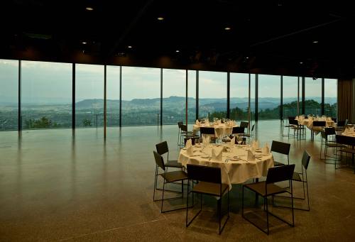 dezeen: Exterior curtains draw back across the glazed facade of this hillside events venue in Bern, 