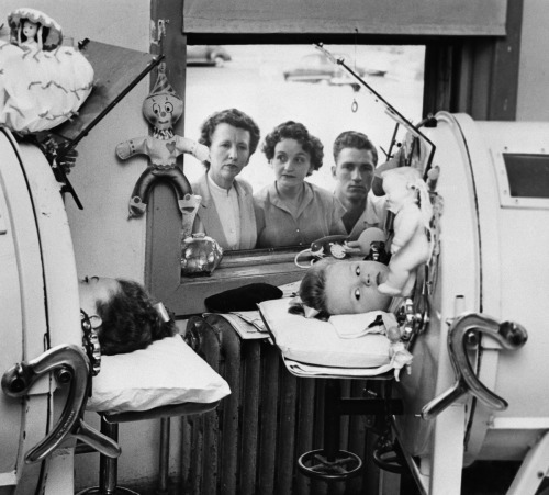 Girls treated for polio in iron lungs, 1952Family members look on as girls are treated for polio in 