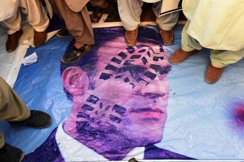 Protestors stand on a poster of the French President Emmanuel Macron during a protest in Quetta, Pak