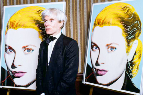  Andy Warhol stands in front of a limited edition serigraph of Princess Grace of Monaco to benefit t