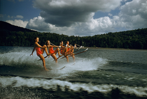 A women&rsquo;s water ski team lifts skis while being towed at 23 mph on Darts Lake in New York,