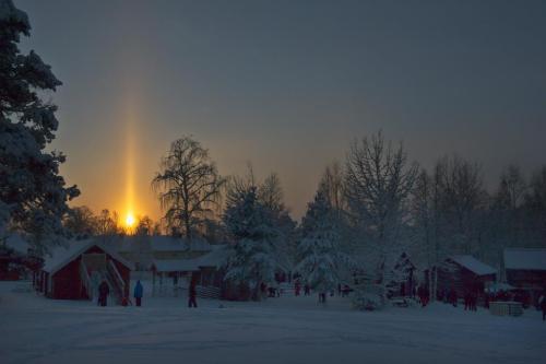 Here is a photo of a stunning a sun-pillar reflecting light from a Sun setting over Östersund, Swede