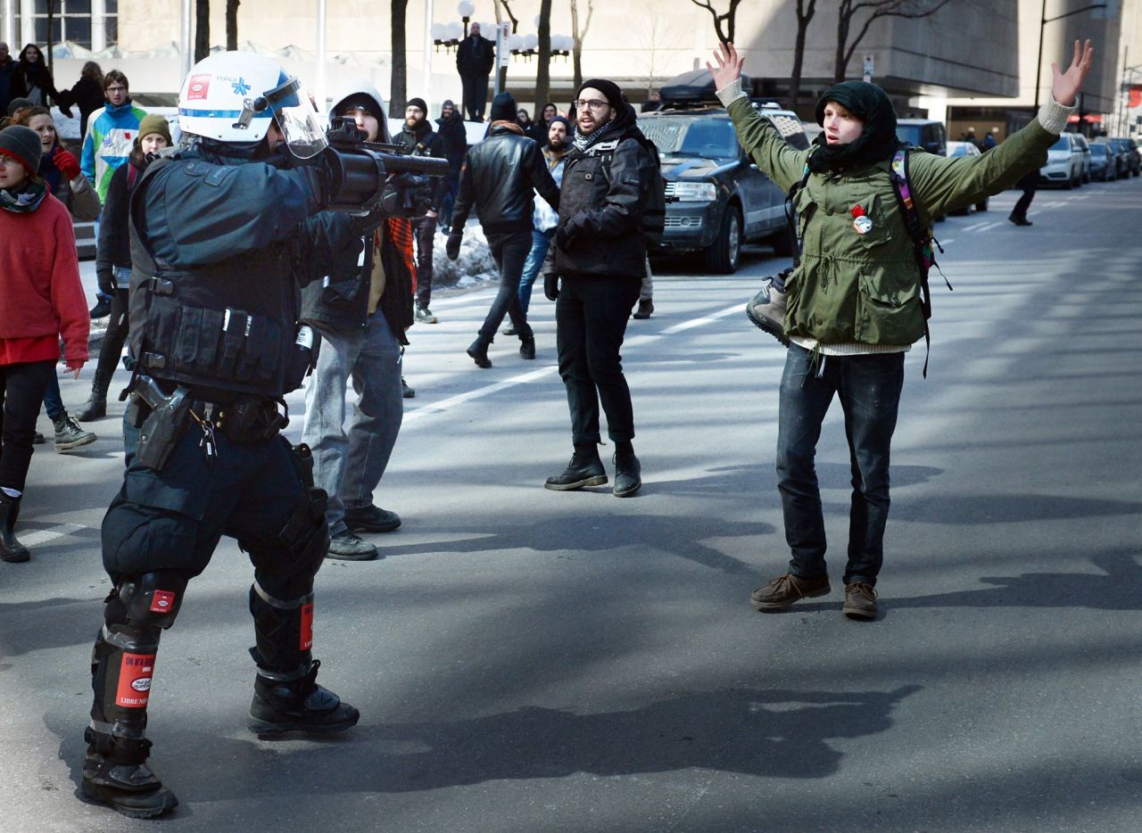 rounxyz:Montreal cop points smoke grenade launcher point back at protester who is