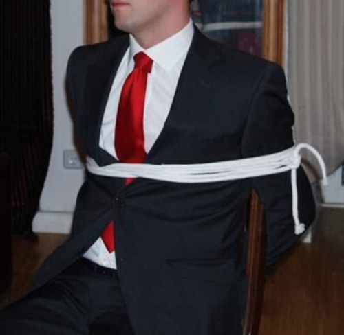 rennegade15:  tied up Businessman in a dark grey suit + white shirt + red tie + white ropes 