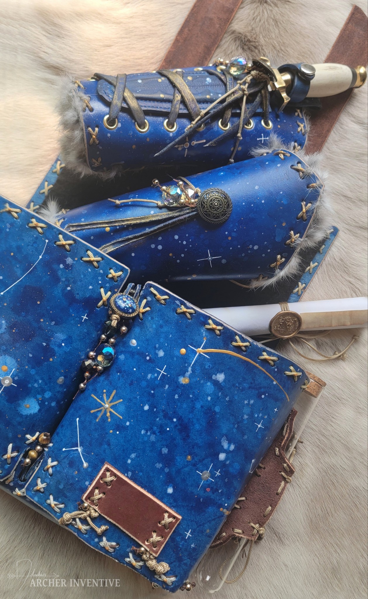 Image is of a navy blue leather bag adorned with gold-painted constellations and gold string
                      in x-patterns sewn into the leather. A glass bottle is tied to the right side. Coming out of the bag is a pair of fur-lined wrist braces once of which sheathes a dagger with a white handle.