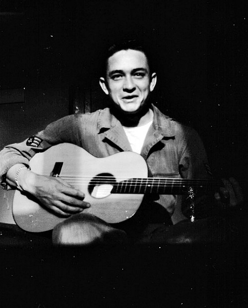  Johnny Cash holds his $10 guitar. He sold appliances door to door before auditioning