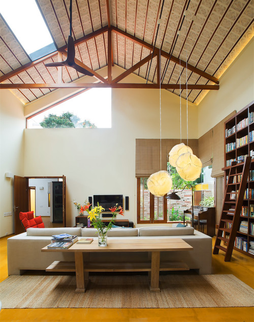 Brightly lit living room under a vaulted ceiling with a bookshelf wall, Bangalore, Karnataka, India 