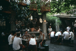dolm:  China. Guangzhou. 1982. People listening to birds. Many people go to tea houses and proudly bring their pet birds in bamboo cages and enjoy listening to the chirping. Hiroji Kubota.