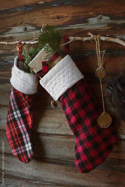 Christmas stockings hung on rustic wall By TanateelAvailable to license exclusively at Stocksy