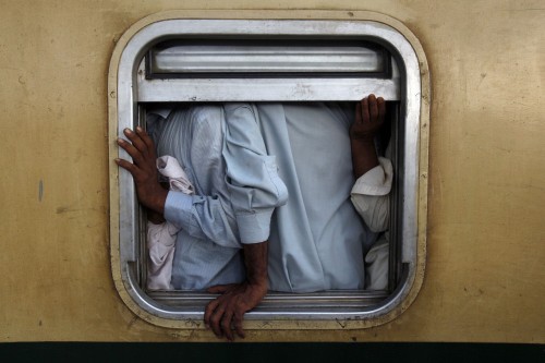 Men are seen at the window of a train as they make their way home at Karachi&rsquo;s Cantonment 