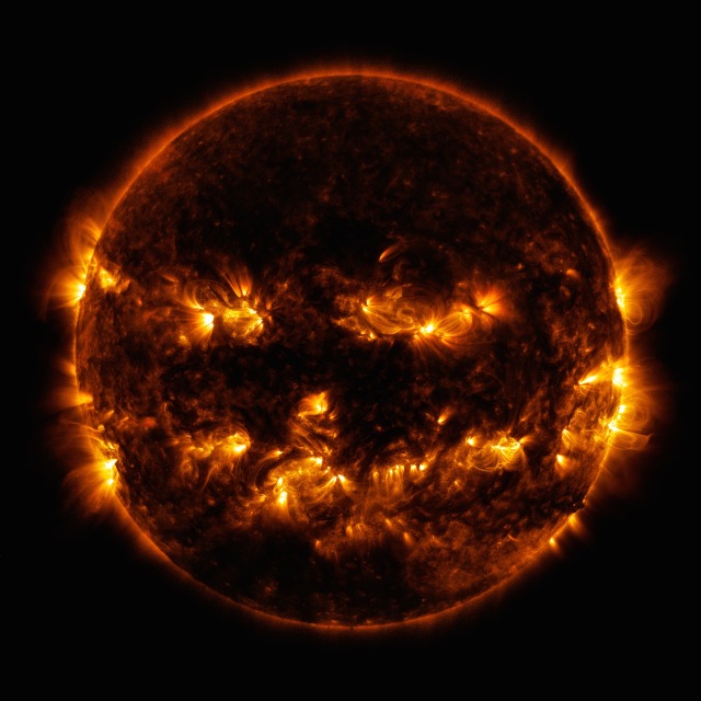 Bright orange active spots make the shape of two eyes and a grin, making the Sun look like a jack-o'-lantern. The rest of the Sun is dark in comparison, with an orange outline distinguishing the star from the darkness of space.

Credit: NASA/SDO