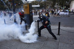 libertariantimes:  An anti-government demonstrator throws a teargas canister after it was thrown at protesters by the police, during clashes at Altamira square in Caracas February 27, 2014. (Reuters/Tomas Bravo)